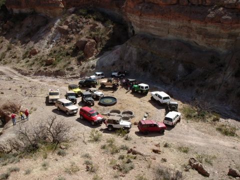 1996 Ford Bronco - Multiple off-road vehicles are parked in a circular formation in a rocky, arid landscape.