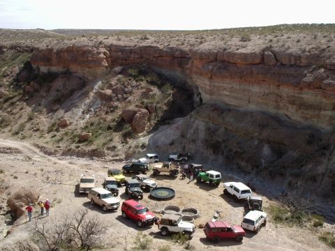 1996 Ford Bronco - A group of off-road vehicles are parked in a circle in a desert canyon landscape.