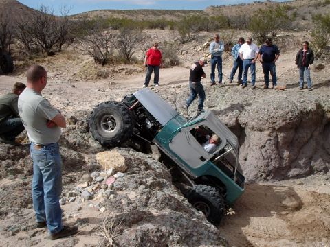 1996 Ford Bronco - An off-road vehicle is stuck on a steep, rocky trail while onlookers observe the situation.