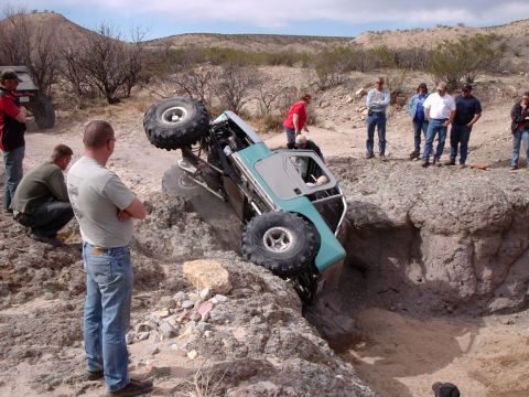 1996 Ford Bronco - A group of people observe an off-road vehicle that has become stuck in a rocky ditch.