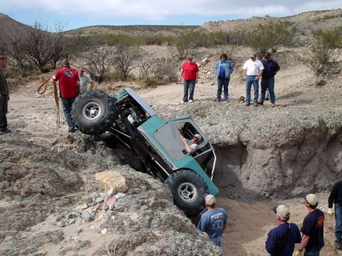 1996 Ford Bronco - An off-road vehicle navigates a steep dirt ravine, with onlookers observing the challenging terrain.