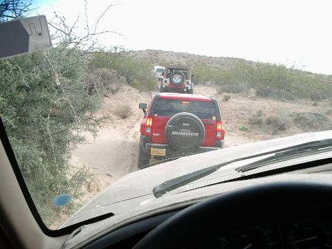 1996 Ford Bronco - A convoy of off-road vehicles navigates a sandy trail in a dry, arid environment.