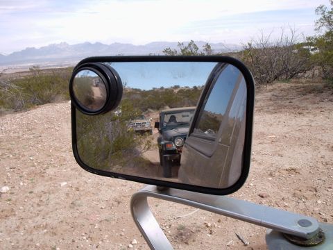 1996 Ford Bronco - A convoy of off-road vehicles navigates a dusty trail through a desert landscape.