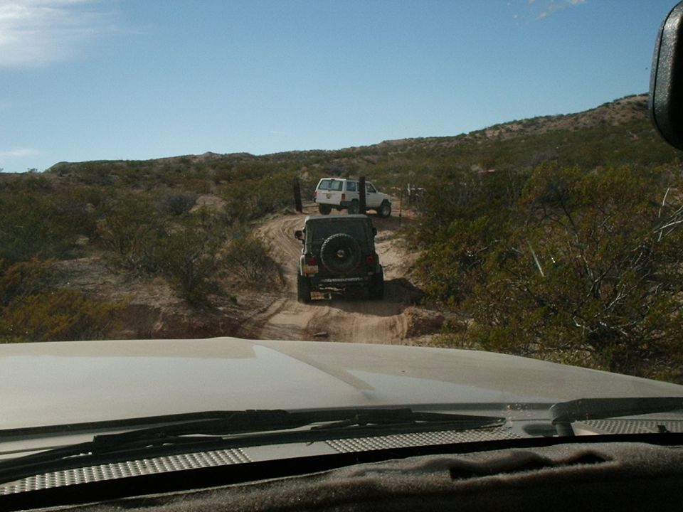 Two SUVs driving on a dirt road in a desert landscape