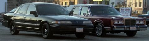 1989 Lincoln Town Car - Two sedans, a black Ford Crown Victoria and a maroon Lincoln Town Car, are parked next to each other.