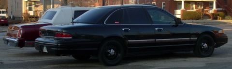 1989 Lincoln Town Car - A black sedan is parked alongside a maroon sedan on a street.