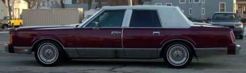 1989 Lincoln Town Car - Side view of a maroon 1989 Lincoln Town Car a white vinyl roof and wire wheels.