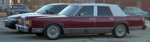 1989 Lincoln Town Car - A maroon sedan with a vinyl roof is parked on a street next to other vehicles.