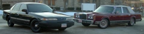 1989 Lincoln Town Car - A black Ford Crown Victoria and a maroon Lincoln Town Car are parked next to each other on a street.