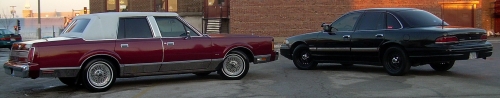 Maroon sedan with white vinyl top parked next to a black sedan