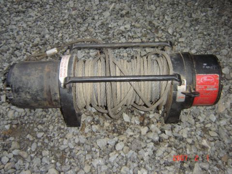 1993 Ford Bronco - A winch with a coiled cable is shown resting on a bed of gravel.