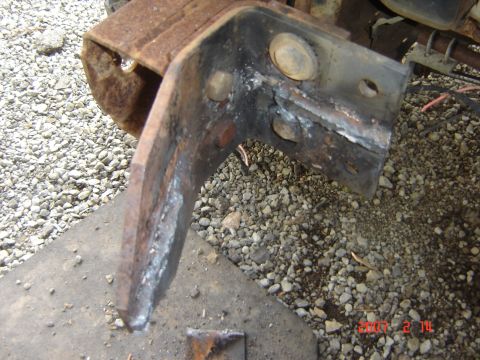 1993 Ford Bronco - A close-up view of a heavily rusted metal bracket, showing signs of welding and mounting holes.