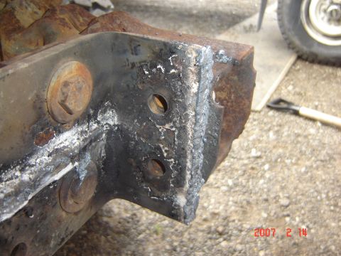 1993 Ford Bronco - This photo shows a heavily rusted metal bracket, likely a vehicle part, with visible bolts and welding.