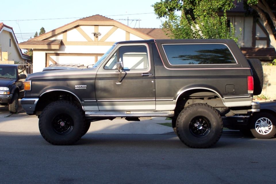 Dark gray Ford Bronco with lifted suspension and large tires, seen from the side