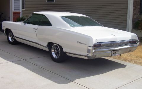 1965 Pontiac Catalina - The rear of a white 1965 Pontiac Catalina is visible, parked in front of a house.