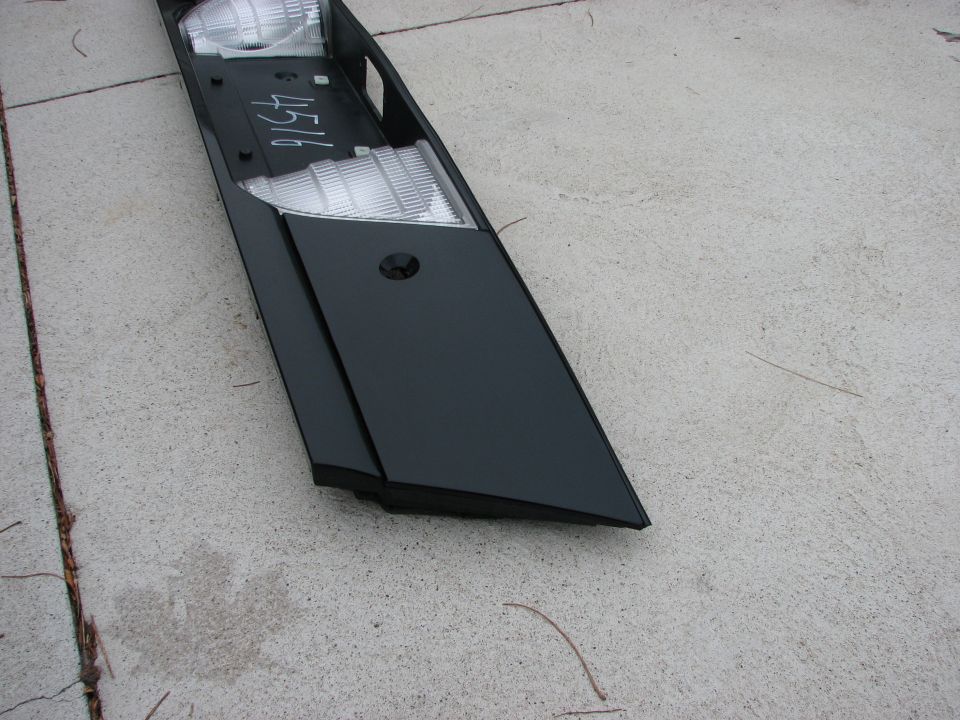 Black car trim piece with clear lights and handwritten number 4516 on concrete