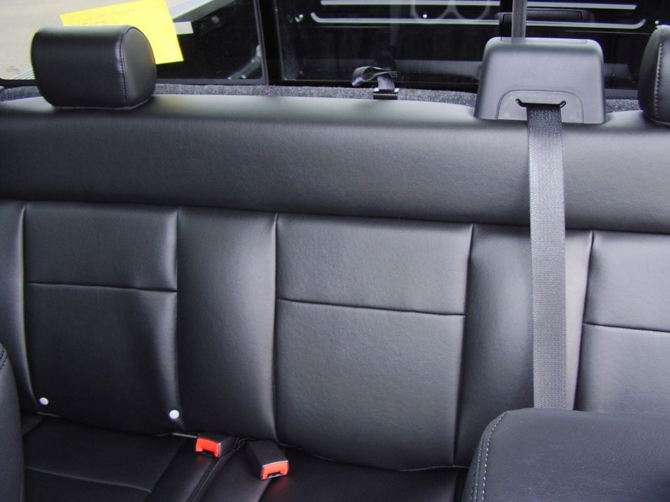 Black leather rear bench seat interior of a pickup with seat belts and headrests