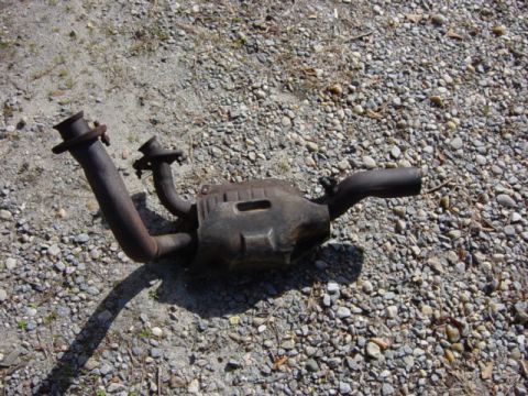 1991 Ford Bronco - An exhaust catalytic converter is shown lying on a gravel surface.