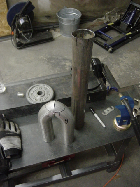 1991 Ford Bronco - Metal exhaust pipe components are laid out on a workbench, ready for fabrication.
