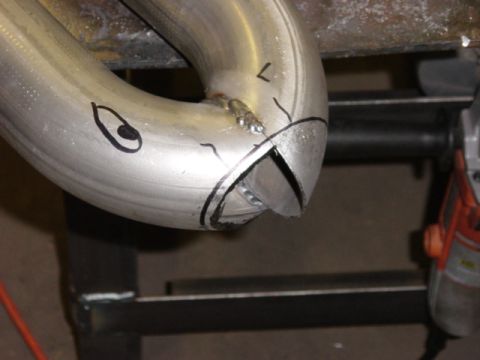 1991 Ford Bronco - A section of exhaust pipe is marked for cutting and welding, with a cartoonish eye drawn on its surface.