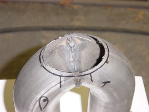 1991 Ford Bronco - Close-up of a metal exhaust pipe section showing weld marks and cut lines.