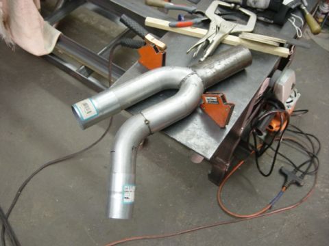 1991 Ford Bronco - Custom exhaust Y-pipe assembly on a workbench with various tools and welding supplies.