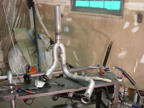 1991 Ford Bronco - A custom exhaust pipe assembly is shown on a workbench, surrounded by tools and materials.