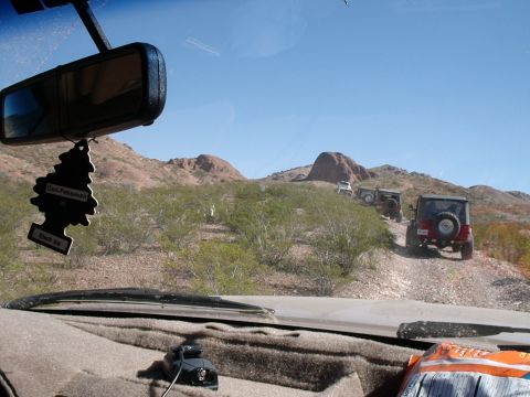 1996 Ford Bronco - A convoy of Jeeps navigates a desert trail under a clear blue sky.