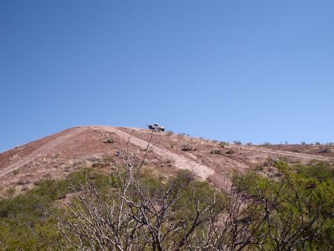 1996 Ford Bronco - A white SUV navigates a dirt track on a barren hillside.