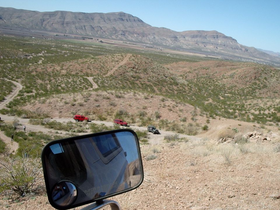 Off-road vehicles on a dusty trail with mountains in the background