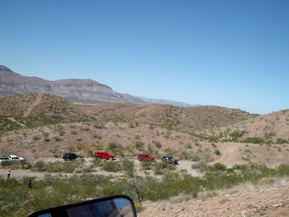 Off-road vehicles on a desert trail with mountains in the background