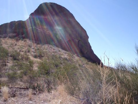 1996 Ford Bronco - A large rock formation dominates the landscape under a clear blue sky with sun flares.