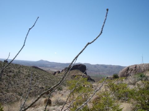 1996 Ford Bronco - A wide view of a dry, hilly terrain with sparse vegetation and large rock formations under a bright, cloudless sky.