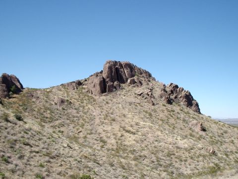 1996 Ford Bronco - A large rock formation dominates a dry, grassy hillside under a bright blue sky.
