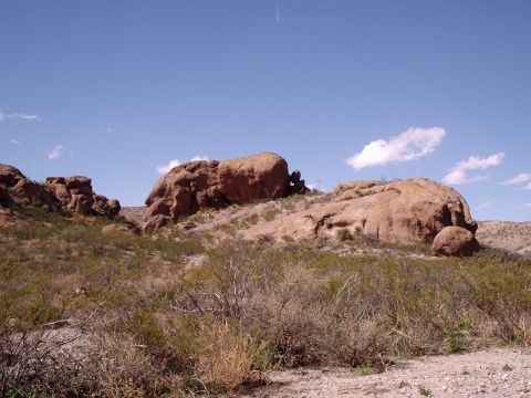 1996 Ford Bronco - A wide view of a desert terrain with prominent rock formations and dry brush under a clear blue sky.