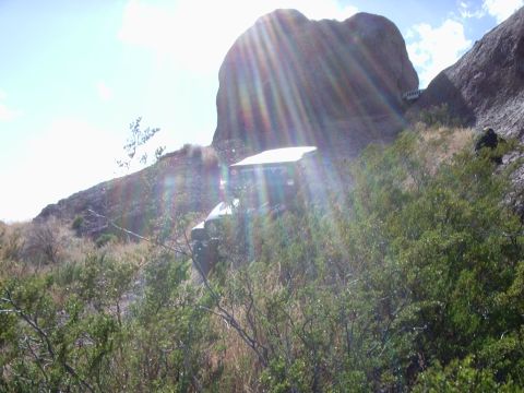 1996 Ford Bronco - A vehicle is parked on a steep, vegetated slope with large rock formations above.