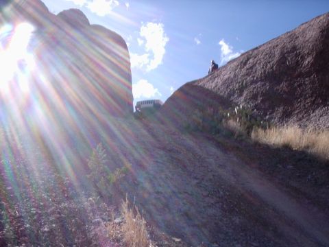 1996 Ford Bronco - A white SUV navigates a steep, rocky terrain under a bright, sunlit sky.