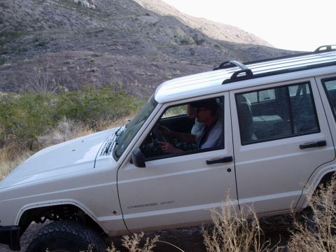 1996 Ford Bronco - A white Jeep Cherokee Sport navigates an off-road trail with two occupants.