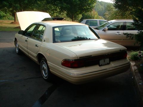 1996 Mercury Grand Marquis - A tan 1996 Mercury Grand Marquis is parked outdoors with its hood and sunroof open, alongside another vehicle.