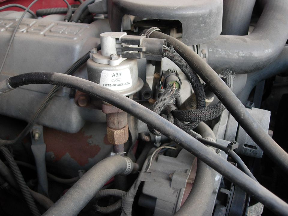 Close-up of engine parts, including hoses and a silver component with a label reading A33