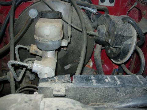 1990 Ford Bronco - Close-up view of the brake master cylinder and vacuum booster assembly in a vehicle's engine bay.