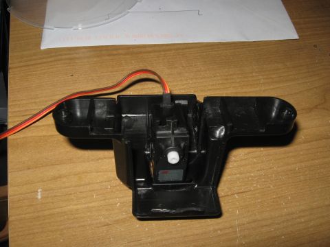 1990 Ford Bronco - Close-up of a servo motor assembly with wiring, resting on a wooden surface.