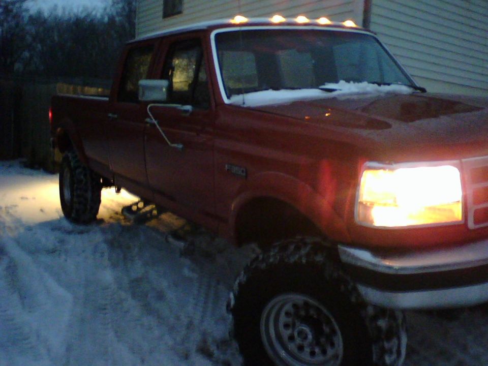 Red 1991 Ford F-350 truck with snow on its roof and hood, parked in a snowy area