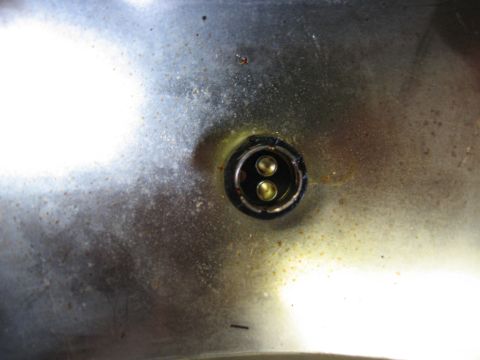 1968 Shelby GT500 - A tarnished metal surface shows a socket with two brass electrical contacts, likely from a vehicle's tail light assembly.