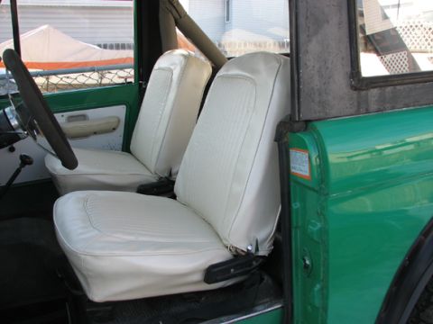 1975 Ford Bronco - The interior of a 1975 Ford Bronco features white vinyl seats and a green exterior.