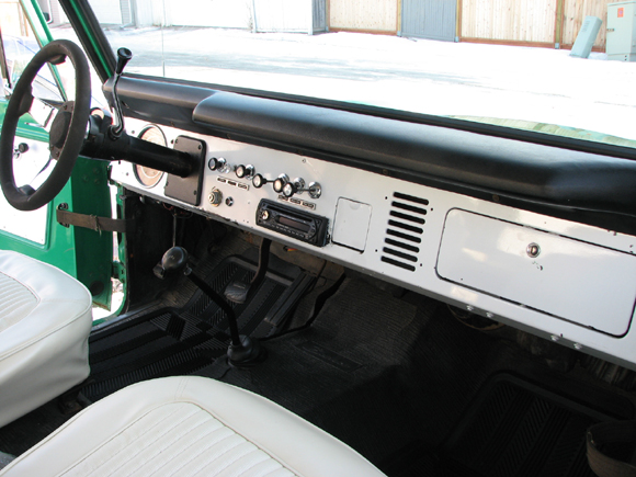 1975 Ford Bronco interior with white seats, black dashboard, and chrome trim