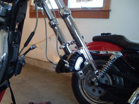 2000 Harley-Davidson Sportster - Close-up view of the front brake caliper and suspension system on a motorcycle.