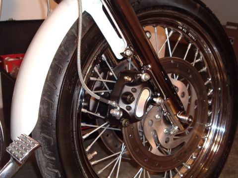 2000 Harley-Davidson Sportster - Close-up view of a motorcycle's front wheel assembly, showing the tire, spokes, and braking system.