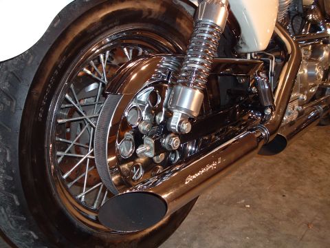 2000 Harley-Davidson Sportster - Close-up of a motorcycle's rear wheel, chrome exhaust, and suspension system.