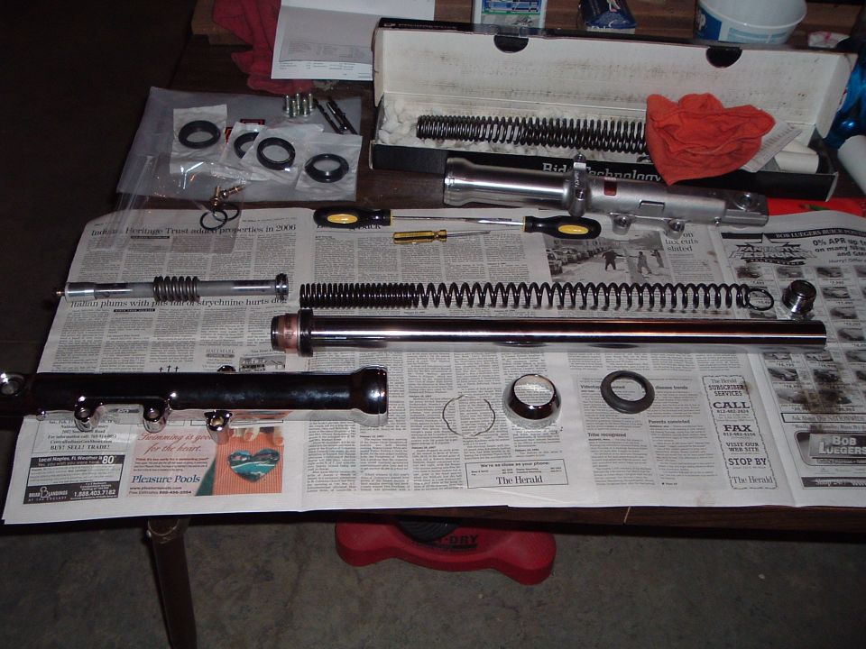Disassembled motorcycle front fork parts laid out on newspapers